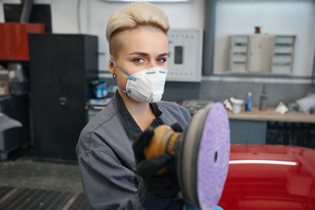 Woman employee looking at camera during car buffingの写真素材
