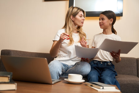 Kind mother and beautiful daughter passionately talking indoorsの写真素材