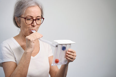 Elderly female patient uses a lung trainer after surgeryの写真素材