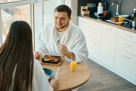 Pleasant young couple chatting at breakfast in a cozy atmosphereの写真素材