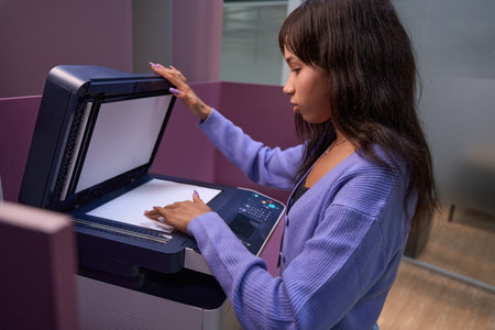 Serious woman worker using multifunction printer in office