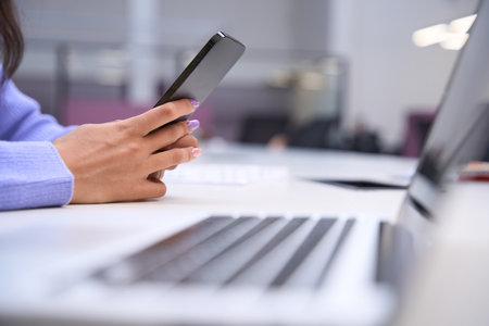 Cropped view of woman browsing cell phone indoors