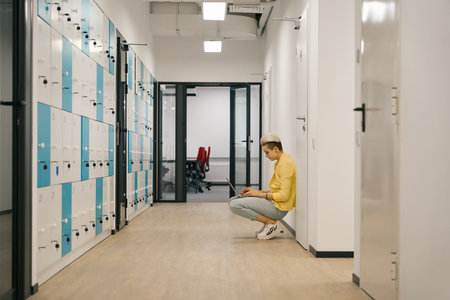 Woman sitting near wall and working on laptop