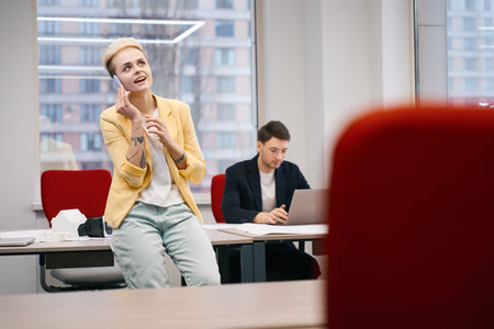Woman manager talking phone while male designer working on project