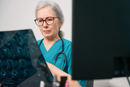 Beautiful elderly female doctor holds an MRI scan of brainの写真素材