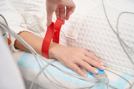 Female diagnostician attaches sensors to the patients arms for an ECG study