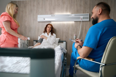 Caring doctor providing healthcare to woman patient in hospitalの写真素材