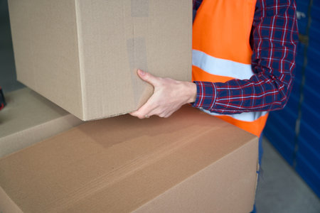 Close-up of large cardboard box in the mans hands of workerの写真素材
