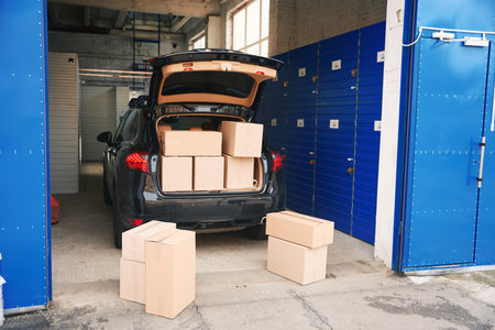 Car with cardboard boxes in the trunk into a warehouse with self-storage unit