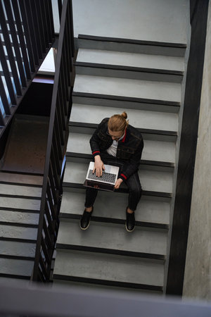 Handsome male using notebook computer in stairwellの写真素材
