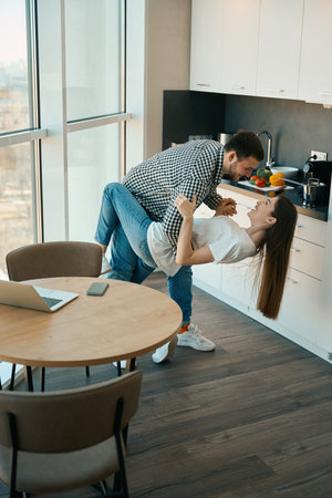 Cheerful beautiful young couple dancing tango in the kitchenの写真素材