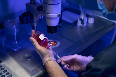 Laboratory worker taking fluid sample with syringe