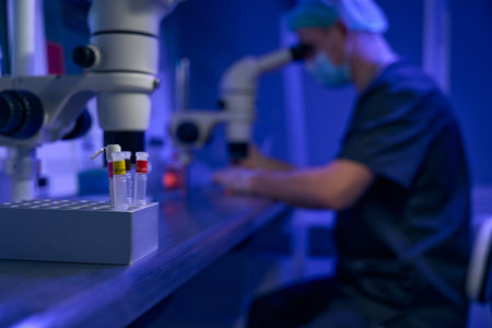 Laboratory worker examining samples under microscope in clinic