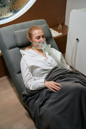 Female in a special mask is located in comfortable chair
