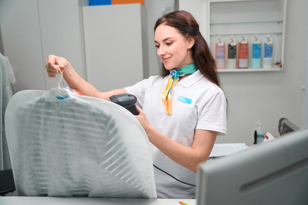 Woman washhouse worker scanning tag on clothesの写真素材