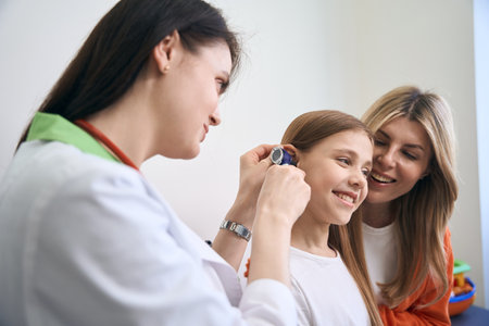 ENT specialist using otoscope with light to check ear to girl patientの写真素材