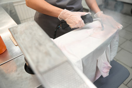 Skilled dry-cleaner using steam gun to remove stain from t-shirtの写真素材