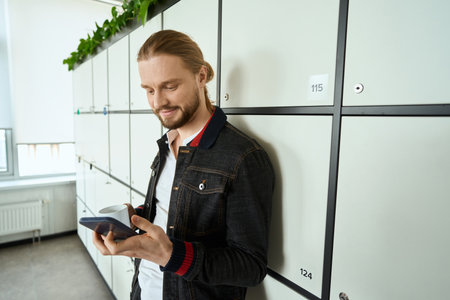 Guy in casual clothes is standing at lockers in coworking space