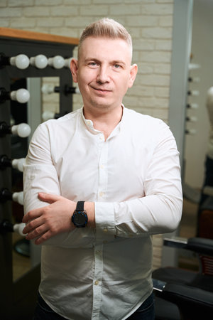 Blond man in a light shirt is standing in roomの写真素材