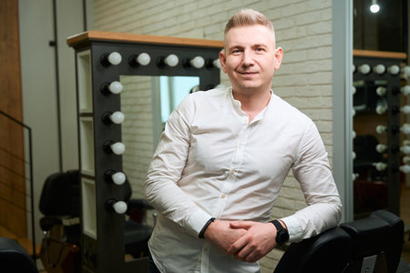 Barber in a light shirt stands at the workplaceの写真素材