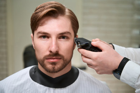 Master hairdresser at the workplace works with a male clientの写真素材