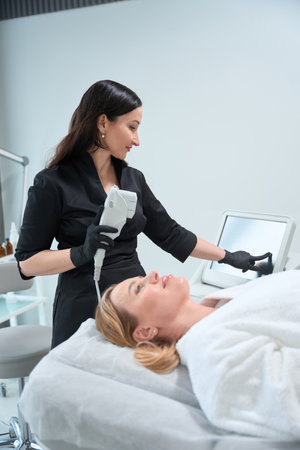 Specialist esthetician adjusts the device for a rejuvenating procedureの写真素材