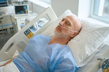 Man with nose tubes lying on the bed in intensive care