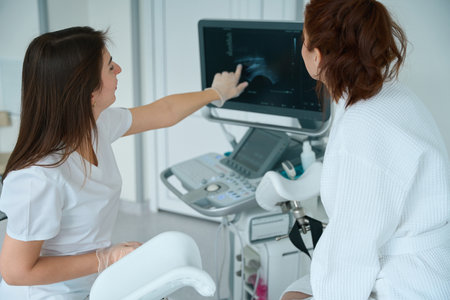 Physician showing to female patient ultrasound image at clinicの写真素材