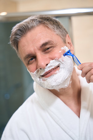 Adult man using razor in the hotelの写真素材