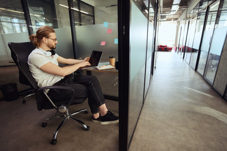 Young employee with a headset sits in comfortable office block