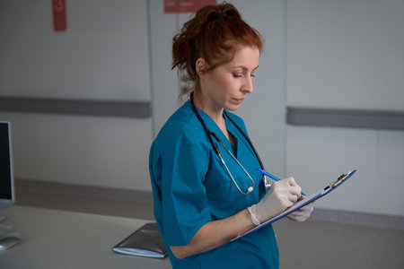 Female physician writing on clipboard in the hospitalの写真素材