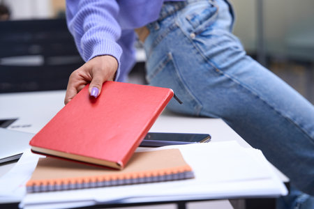 Hand of woman taking copy book indoorsの写真素材