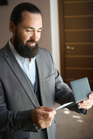 Bearded man holds a ticket and passport in his handsの写真素材
