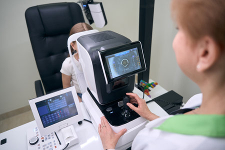 Specialist ophthalmologist examines eyes of young patient on special apparatus