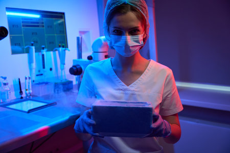 Embryologist laboratory assistant holds a tank with liquid nitrogen in her handsの写真素材