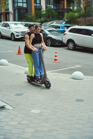 Young woman with her boyfriend are moving around city on scooter