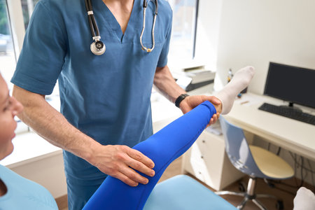 Rehabilitation specialist working with patient leg, straightening and massagingの写真素材