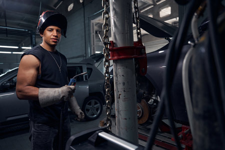 Man holding weld standing protective mask and gloves in garageの写真素材