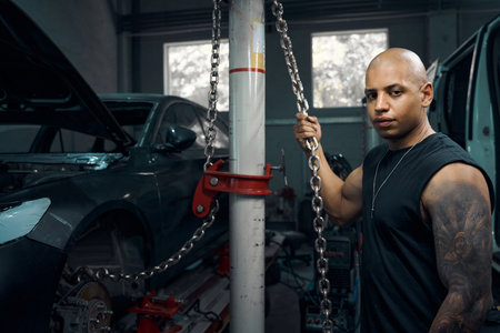 Auto mechanic holding chains that used to raise and lower motor vehicleの写真素材