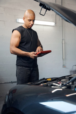 African American auto-mechanic diagnosing car electric system using tabletの写真素材