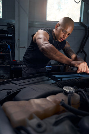 Man with big muscles screwing internal screw with universal screwdriverの写真素材