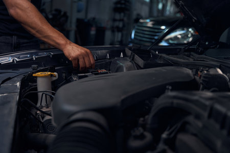 Close-up hand of male auto-mechanic checking battery terminalsの写真素材