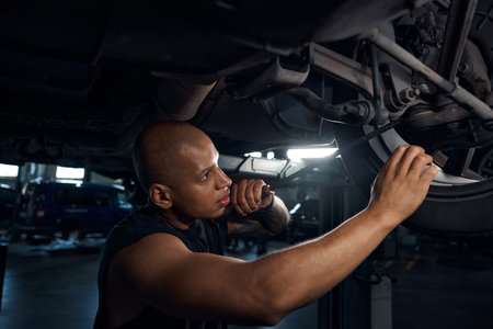 Male worker checking car suspension and wheels conditionsの写真素材