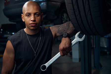 Auto-mechanic holding big socket wrench in hand, looking seriouslyの写真素材