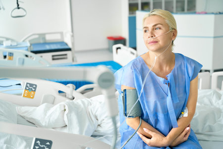 Tired woman is sitting on a special hospital bedの写真素材