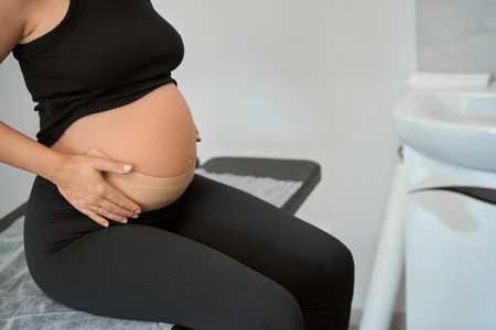Pregnant woman sits on a massage tableの写真素材