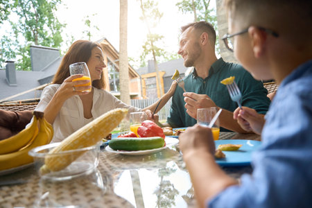Mom, dad and son are talking over lunch on terraceの写真素材