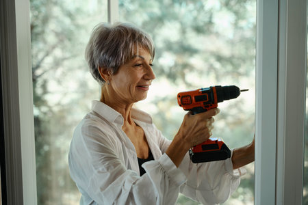 Elderly lady does minor home repairs on her ownの写真素材