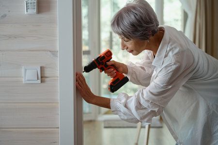 Elderly woman does minor home repairs on her ownの写真素材