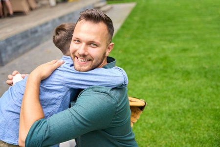 Happy father hugs his son on a green lawnの写真素材
